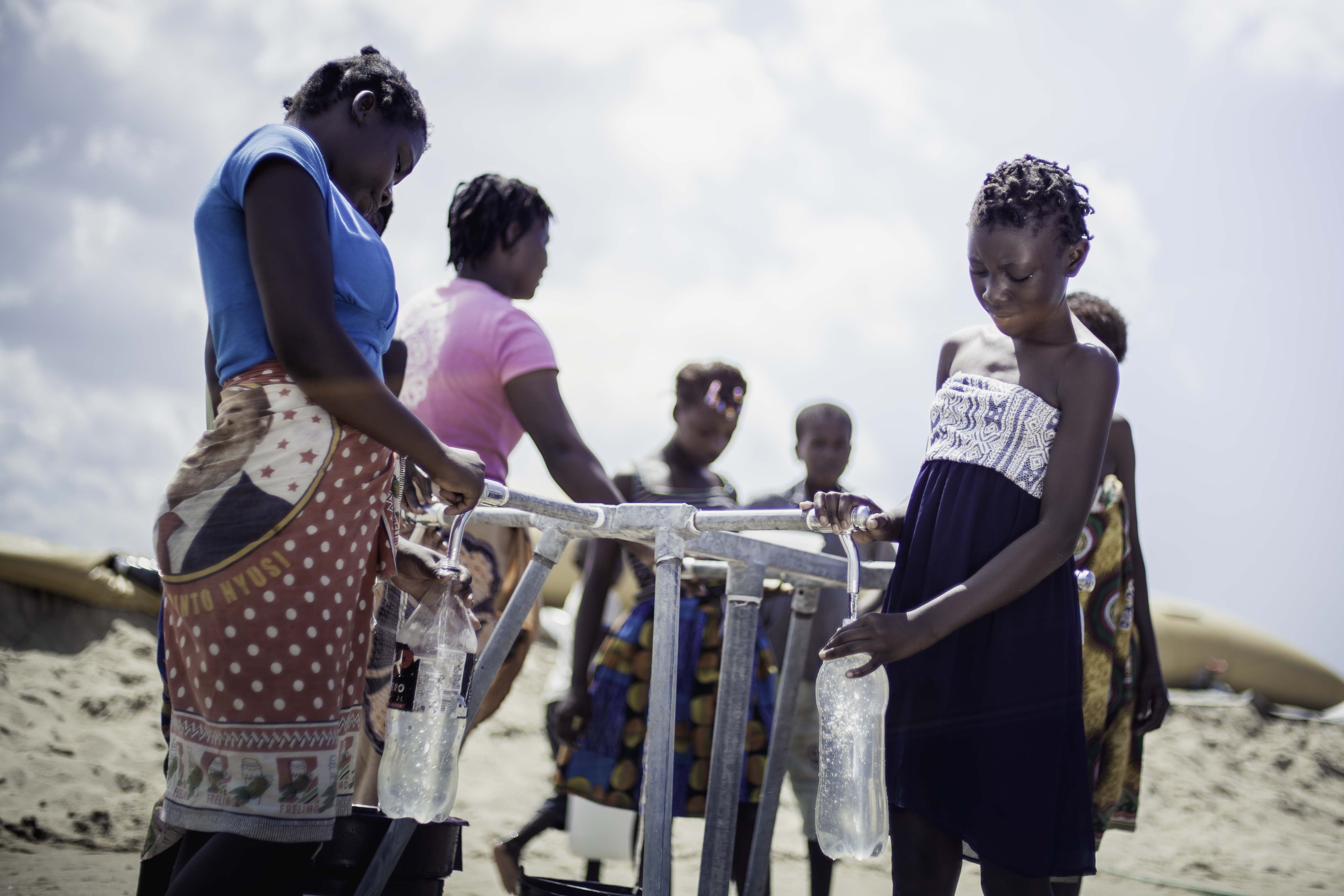 Teresa Jone Vilanculos (right), 14, filling her bottle at the tap stand. She fled her village, Mangalaforte, together with her family when their house was washed away by Cyclone Idai. (Photo: Micas Mondlane / Oxfam Novib)